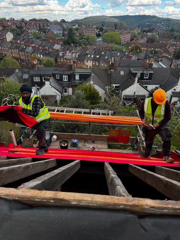 The 247 Roofing team laying membrane on a roof above the town